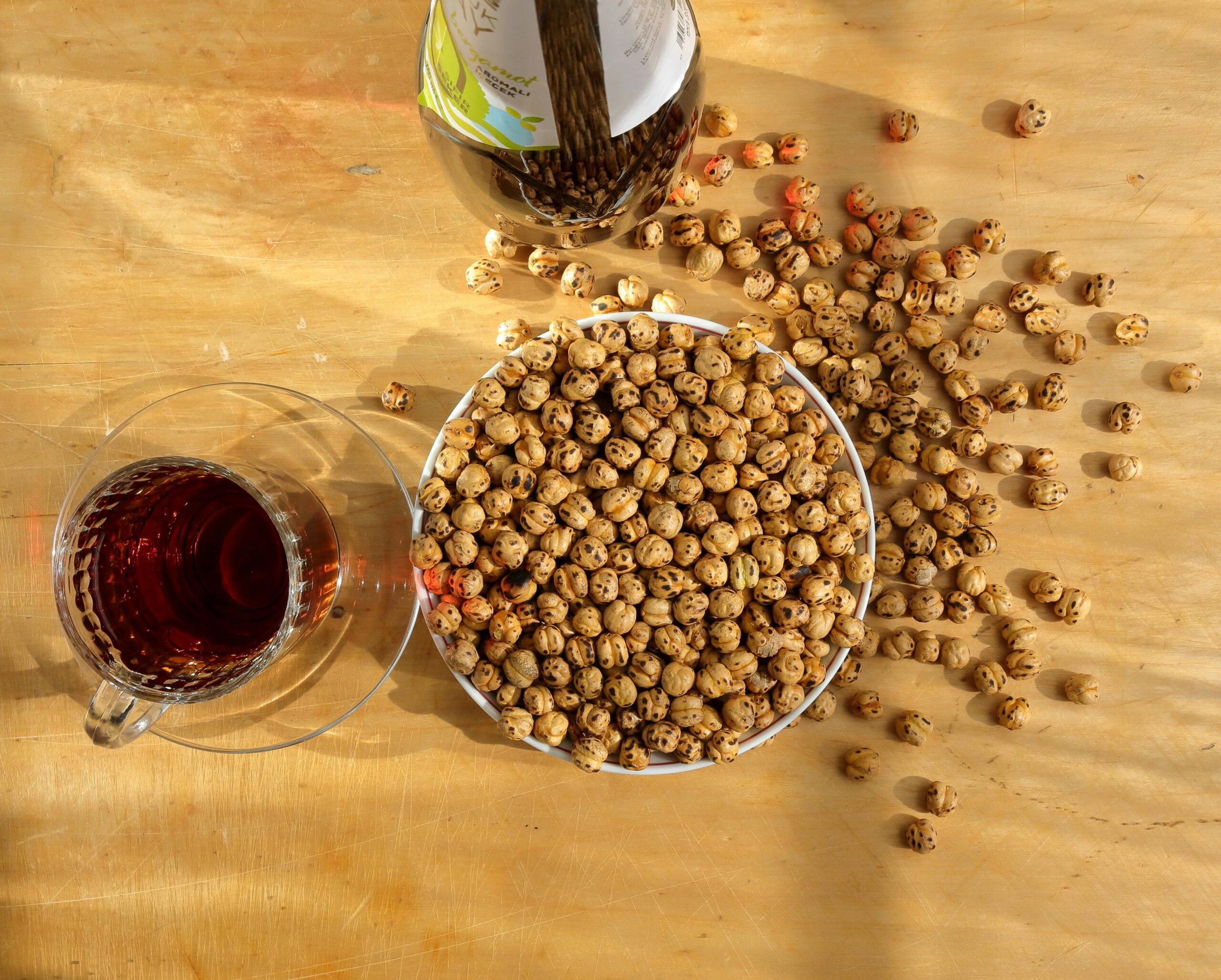 A bowl of dried tiger nuts with a cup of tea, perfect for healthy snacking.