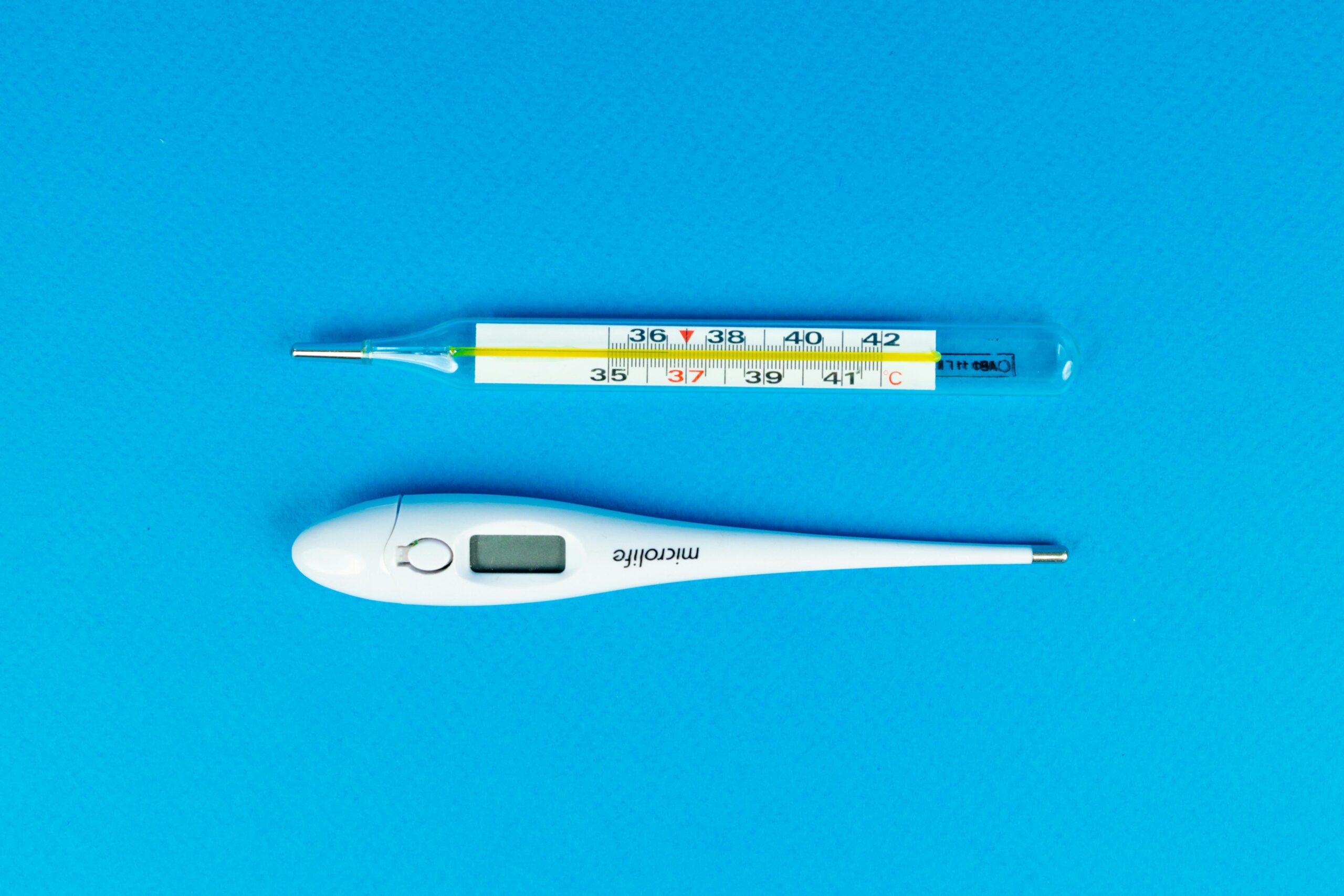 Digital and mercury thermometers on blue background for medical concept.