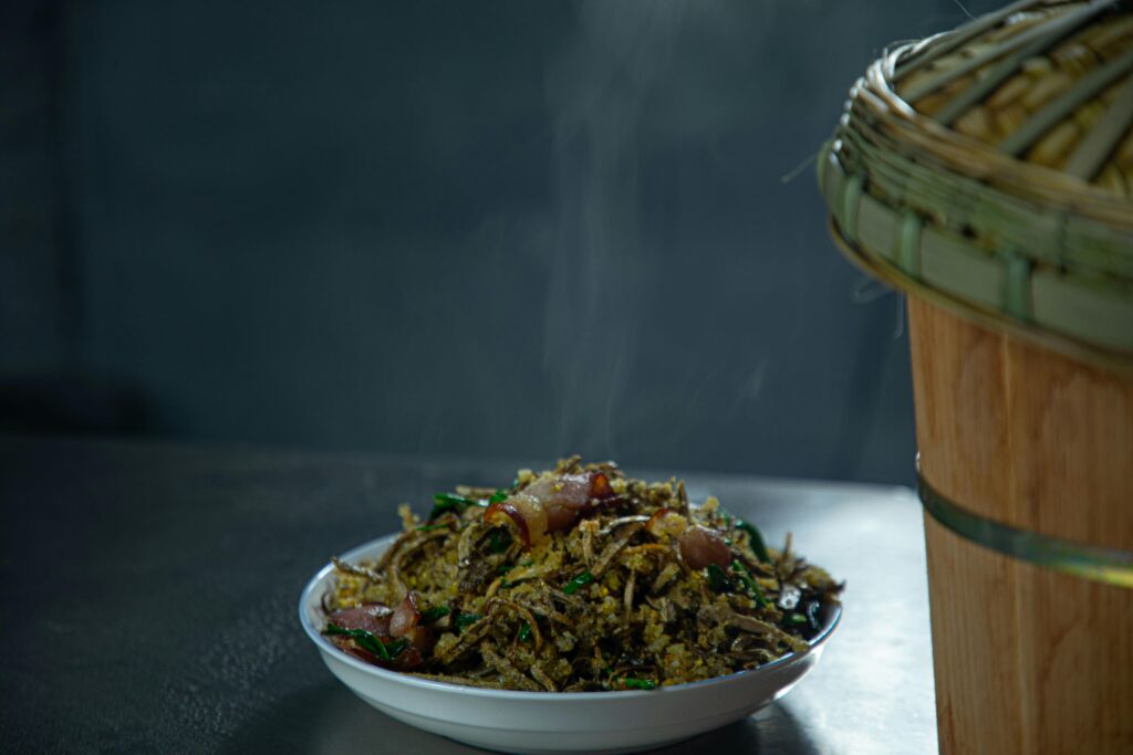 Hot Asian dish with steam rising, served on a plate beside a woven basket.